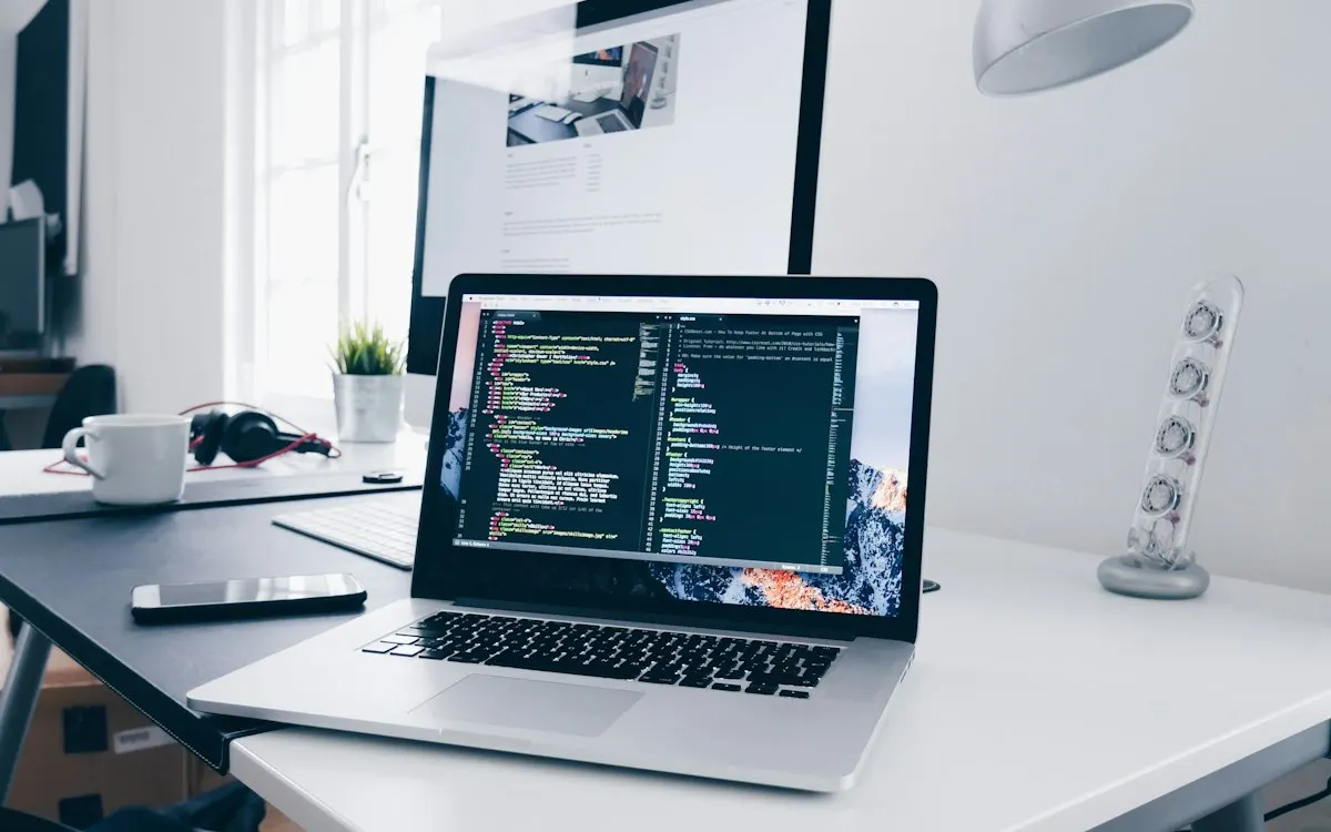 Laptop showing landing page code on a desk